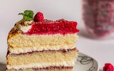 A slice of layer cake with raspberries