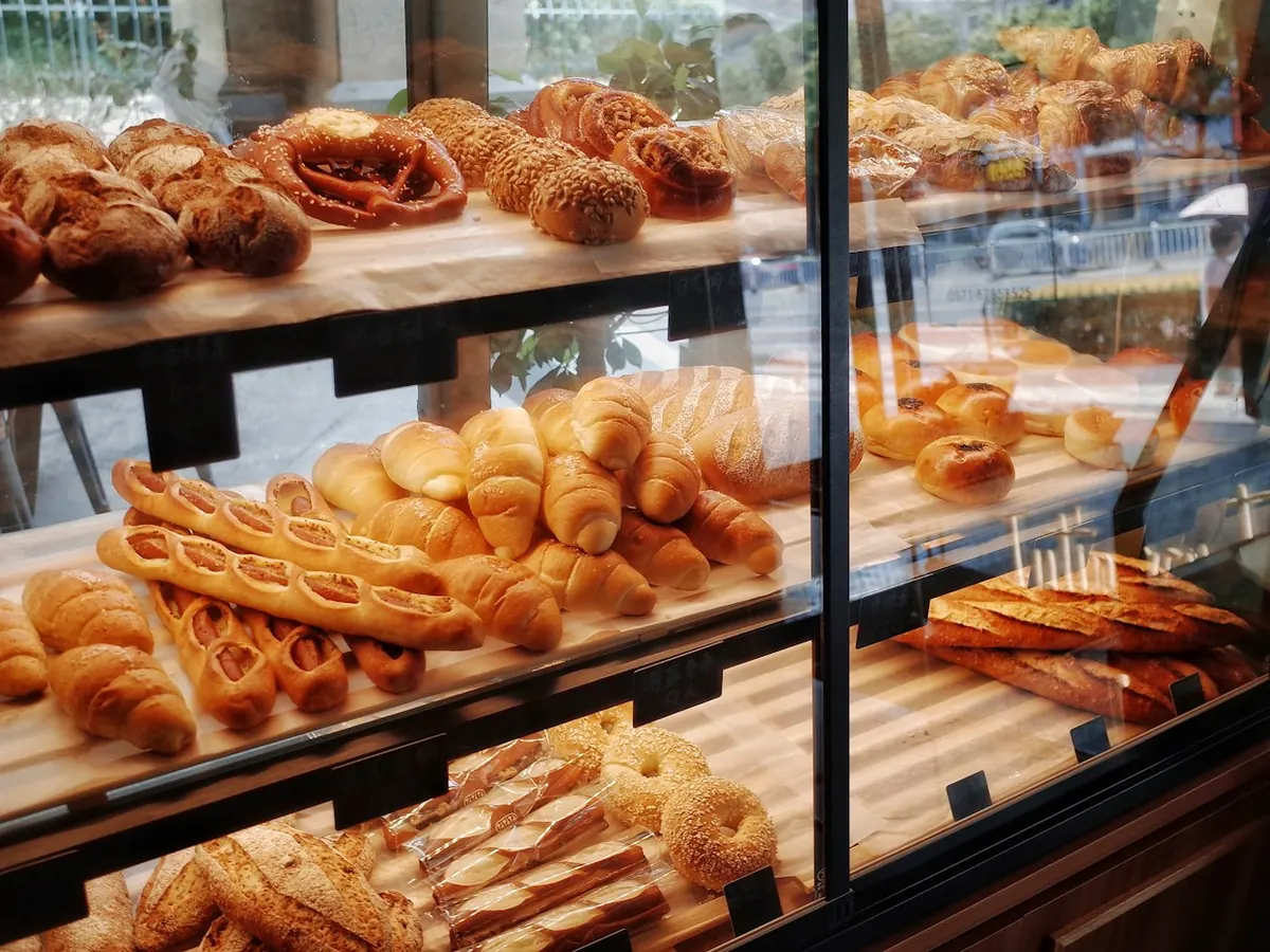 A glass case of fresh croissants, rolls and loaves