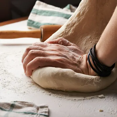 Hands kneading bread dough on a floured table